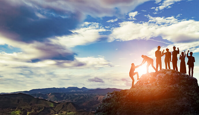 people-celebrating-on-clifftop-against-the-sun-mountain