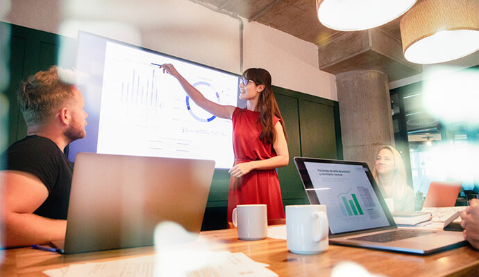woman-in-red-dress-presenting-stats-in-conference-room-reflection