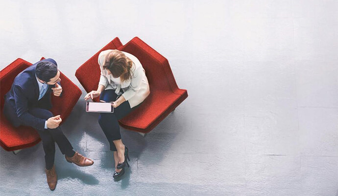 couple-sitting-on-design-red-furniture-working-on-tablet-overhead-view