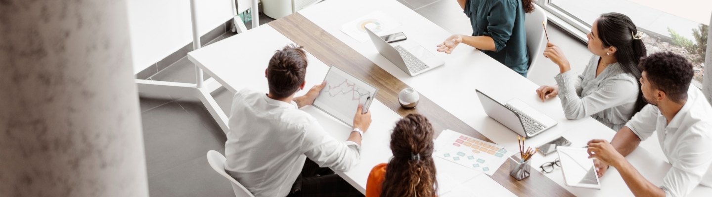 people-sitting-at-table-in-corporate-office-with laptops-1440-x-400
