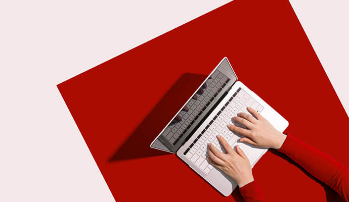 hands-typing-on-laptop-overhead-view-white-red-background