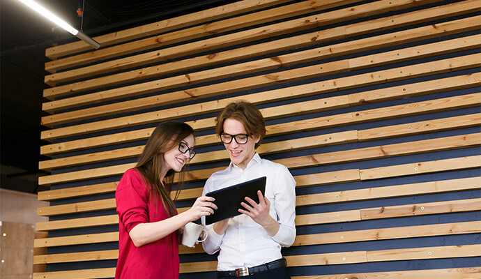 couple-smiling-at-tablet-wooden-wall-background-bdo