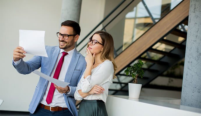 couple-in-office-attire-looking-at-documents-standing-office-setting-bdo