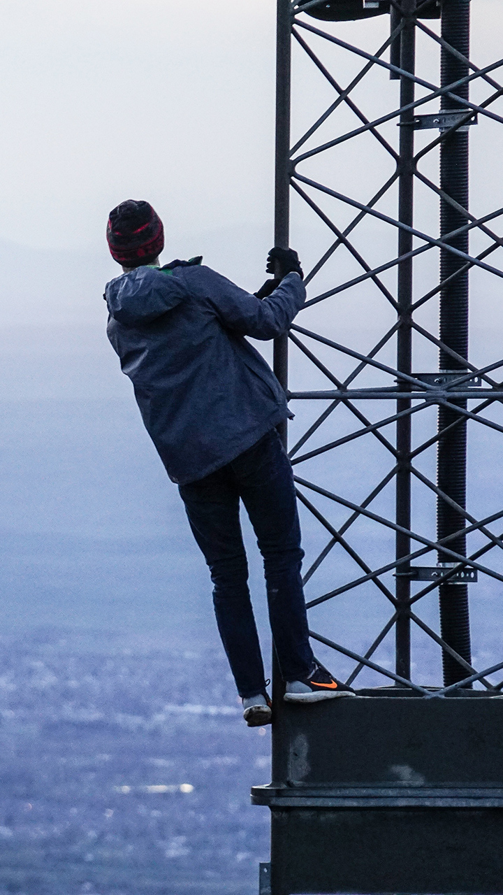man on pylon looking at the ocean