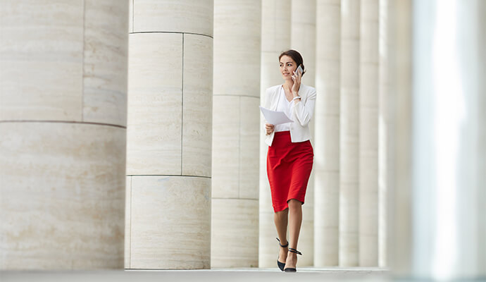 woman-in-office-attire-on-the-phone-walking-column-background-bdo
